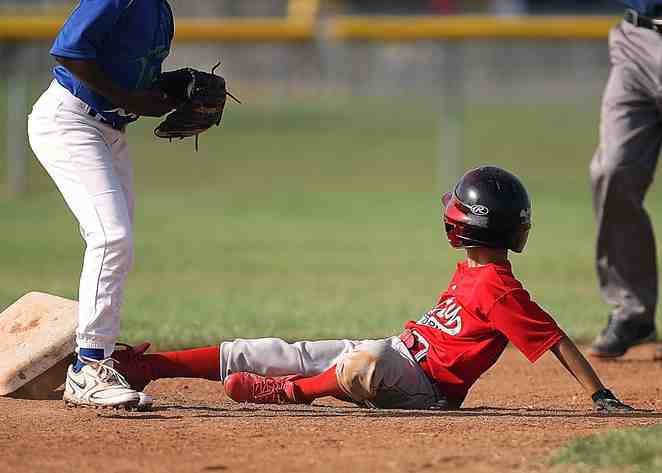 Houston, United States. Little league ball player looks to the umpire for a ruling after sliding into second base.
