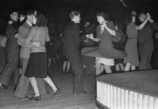 A couple at a British dance hall try out the new jive steps, whilst the rest of the hall continue with old-style ballroom dancing.